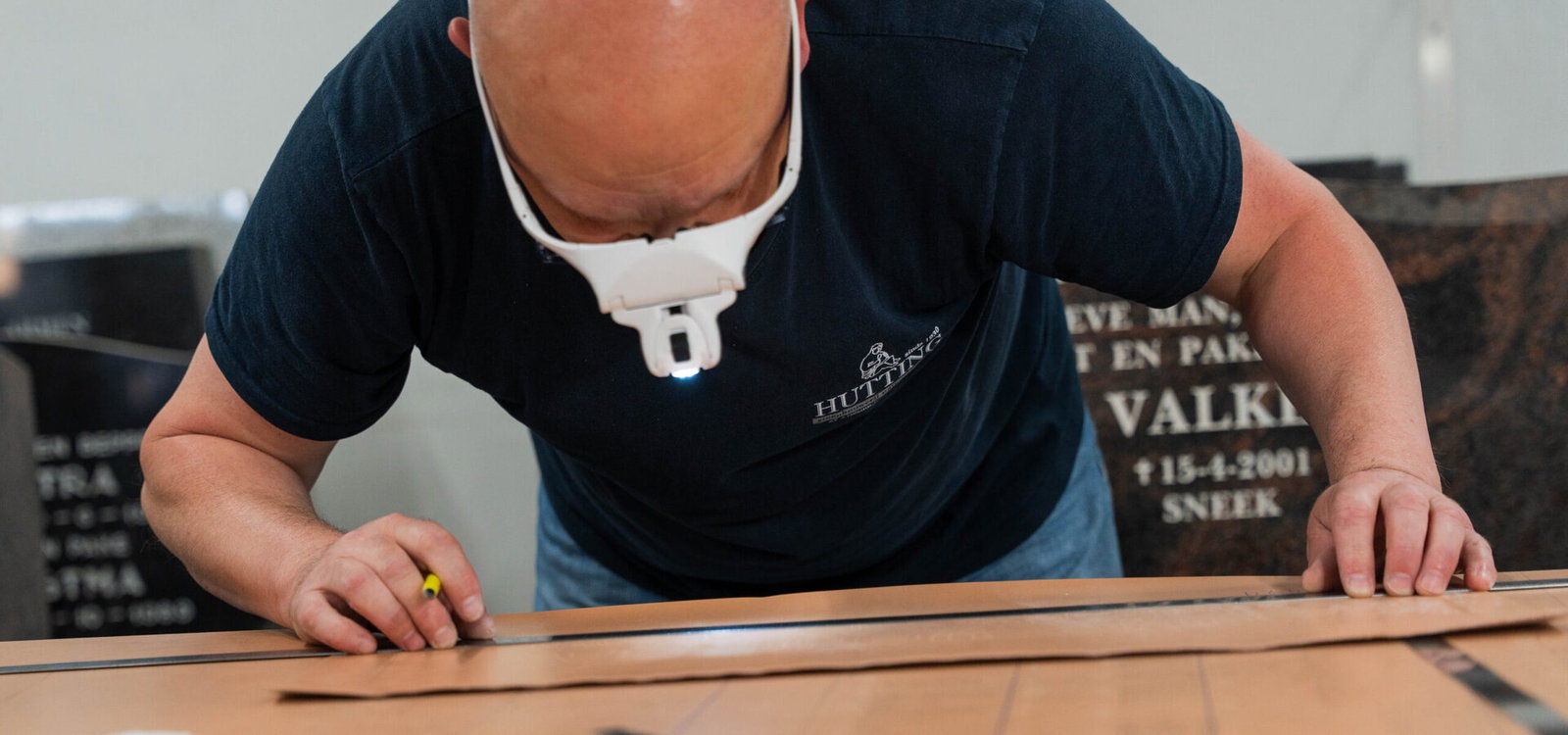 Steenhouwer werkt aan het sjabloon voor de belettering